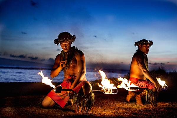 Zwei Männer bereiten sich vor in Hawaii mit Feuer am Strand zu tanzen.  